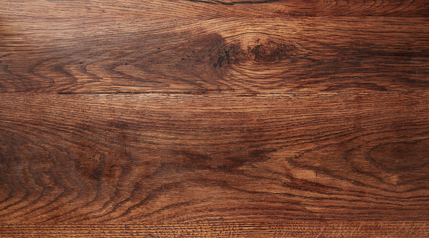 Zoomed in view of the top of a wooden table, showing the wood grain and detail.