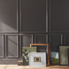 Framed artworks on a wooden surface against a dark paneled wall