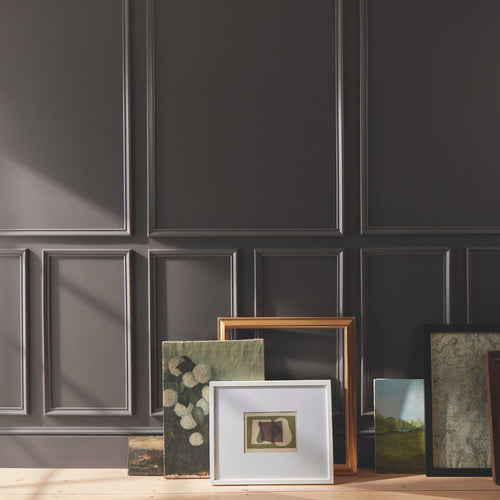 Framed artworks on a wooden surface against a dark paneled wall