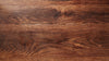 Zoomed in view of the top of a wooden table, showing the wood grain and detail. 